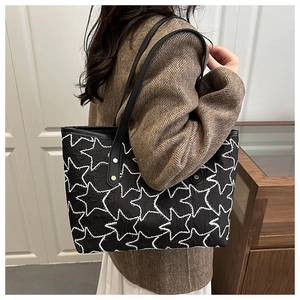 Detail of black tote bag with white star embroidery and pleated texture on model