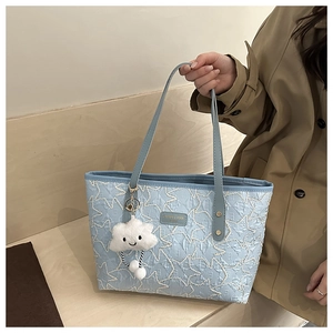 Close-up of light blue star-embroidered tote bag with a soft cloud pendant charm
