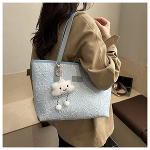 Detail of light blue tote bag with star textured embossing and cloud plush charm detail