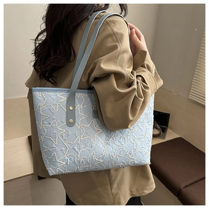 Detail of light blue tote bag featuring white star embroidery and golden metal rivets
