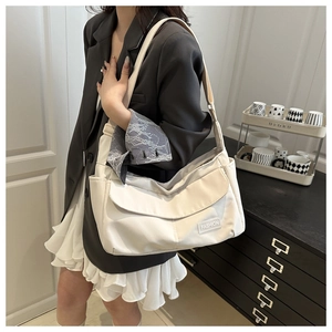 Dettaglio della borsa a tracolla in nylon beige con cinturino regolabile indossata