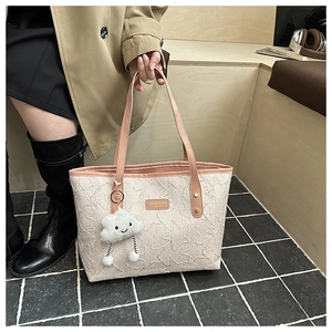 Detail of embroidered tote bag with pink leather strap and a cute cloud charm accessory