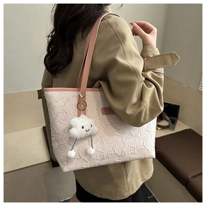 Detail of pink crochet tote bag with a cute plush cloud charm on a trench coat model