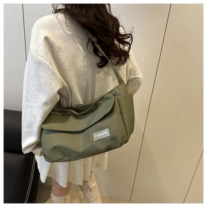 Borsa a tracolla verde scuro capiente con patta e tasche laterali indossata dal modello