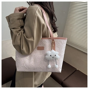 Detail of pink woven tote bag with plush cloud charm and leather shoulder strap