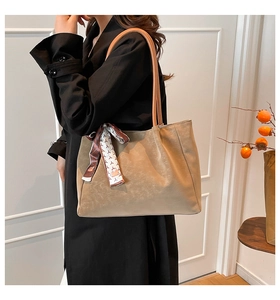 Detail of khaki leather tote bag with silk scarf handle on model for size reference