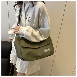 Borsa a tracolla in nylon verde militare con chiusura a patta e cinturino regolabile su camicia