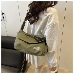Dettaglio della borsa messenger in nylon verde oliva con patch e tracolla larga