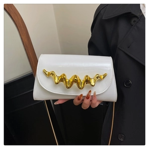 Detail view of a white patent leather evening bag with golden wave metal clasp and chain