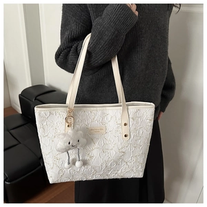 Detail of white pleated tote bag with golden rivets and cute cloud-shaped plush charm