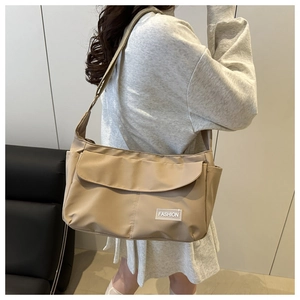 Dettaglio della borsa a tracolla in nylon kaki impermeabile indossata da un modello