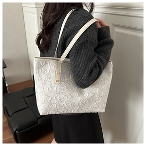 Detail of cream tote bag with star embroidery and leather handles worn by a model