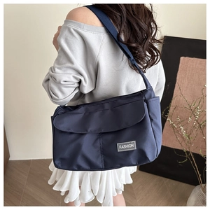 Dettaglio della borsa a tracolla blu navy in nylon impermeabile indossata dal modello