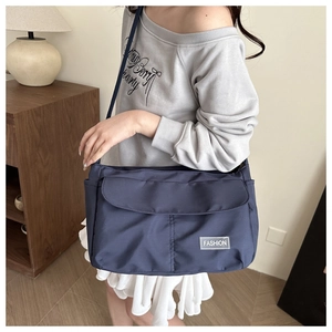 Dettaglio della borsa a tracolla in nylon blu scuro con tasca laterale ed etichetta Fashion