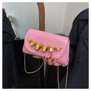Close-up of pink patent leather handbag featuring sculptural gold wave metal ornament