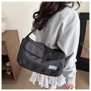 Vista posteriore di una modella con borsa a tracolla in nylon nero ed etichetta fashion