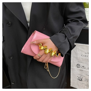 Detail of pink patent leather handbag with wavy gold handle and elegant chain strap