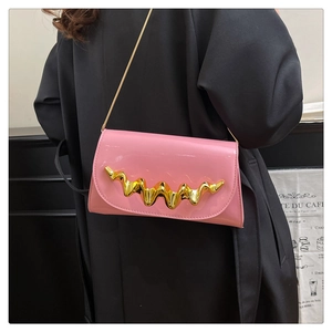Detail of pink patent leather handbag featuring gold wavy metal hardware and chain strap