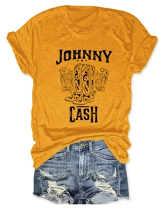 Flat lay of Johnny Cash yellow tee with floral boots graphic and distressed denim shorts