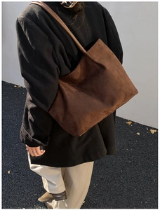 Foto all'aperto di una modella con una grande borsa tote in pelle scamosciata marrone scuro
