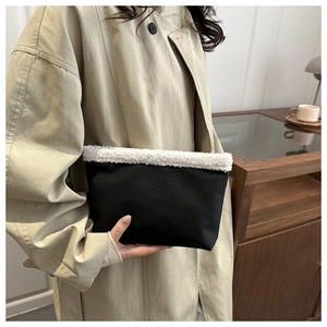 Dettaglio di un'elegante pochette nera con bordo in pelliccia sintetica bianca e modella