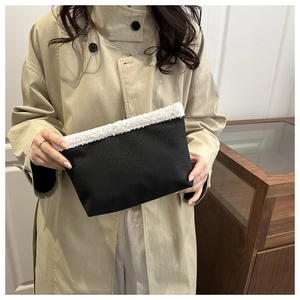 Dettaglio della borsa tote nera con bordo in sherpa bianco tenuta da una modella