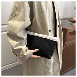 Dettaglio della borsa tote nera minimalista con bordo in shearling sintetico bianco