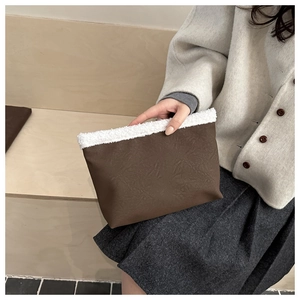 Dettaglio borsa in similpelle con bordo in pelliccia bianca su sfondo dallo stile minimalista