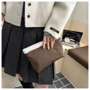 Dettaglio della pochette marrone in finta pelle con bordo in pelliccia sintetica bianca