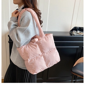 Close-up of pink quilted puffer tote bag with thick shoulder strap on female model