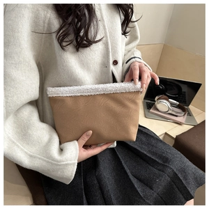 Dettaglio del bordo in ecopelliccia su una pochette in pelle scamosciata marrone