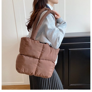 Detail of brown quilted puffer tote bag with soft padded straps on female model