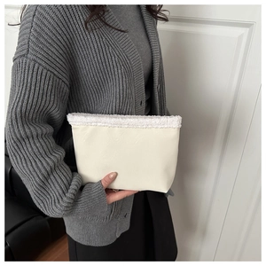 Dettaglio di pochette in ecopelle crema con bordo in sherpa bianco morbido