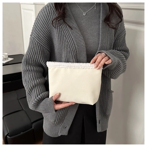 Dettaglio della pochette beige con bordo in morbida pelliccia bianca e trama di pregio