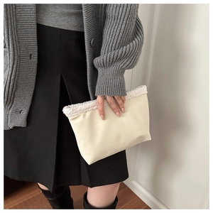 Dettaglio pochette in similpelle crema con bordo in pile bianco e texture elegante