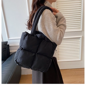 Side view of a black quilted puffer tote bag with soft padding and wide shoulder straps