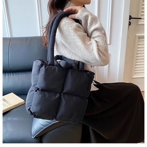 Detail of black quilted puffer tote bag with thick padded handles and large grid design