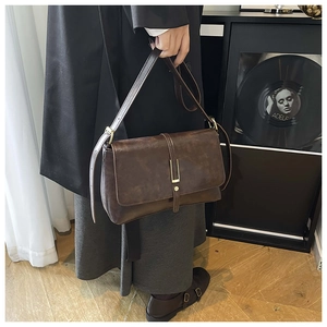 Detail van vintage bruine lederen crossbodytas met gouden gesp en getextureerd leer