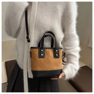 Détail du sac seau matelassé en daim marron avec bordure noire et clous métalliques dorés