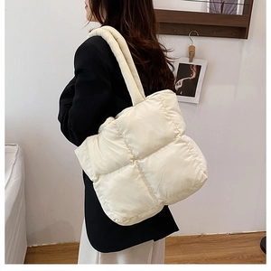 Détail du sac fourre-tout matelassé blanc crème avec large bandoulière sur le mannequin