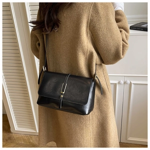 Detail van zwarte retro lederen tas met gouden sluiting op een camel wollen jas
