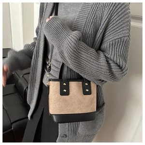 Detail van kaki suède en zwart leer stiksel met ruitvormig patroon op de bucket bag