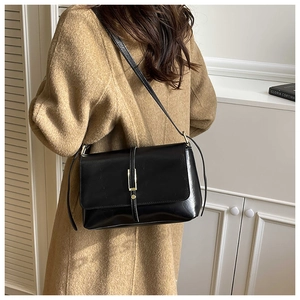 Detail van minimalistische zwarte crossbodytas gecombineerd met een camelkleurige jas