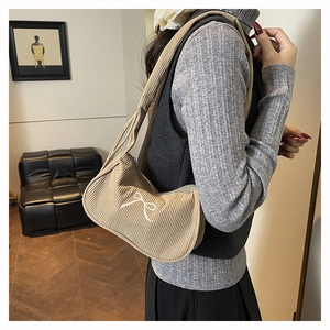 Dettaglio ravvicinato della borsa di velluto a coste beige con ricamo a fiocco bianco