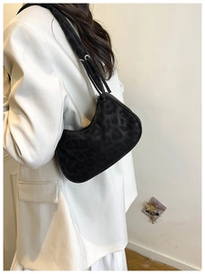 Dettaglio di una borsa hobo chic con stampa leopardata con tracolla su un blazer bianco