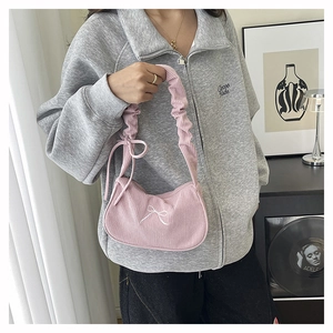 Dettaglio della borsa in velluto a coste rosa con ricamo a fiocco bianco e tracolla arricciata