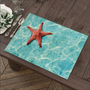 Detail van linnen placemat met rode zeester en waterprint op donkerhouten tafelblad