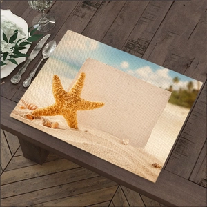 Detail van placemat met zeesterprint op donker hout met wit servies en bestek