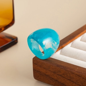 Macro shot of chunky blue marble resin ring showing swirl patterns on a wooden box