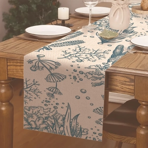 Détail de chemin de table en lin avec motifs marins bleus sur une table en bois
